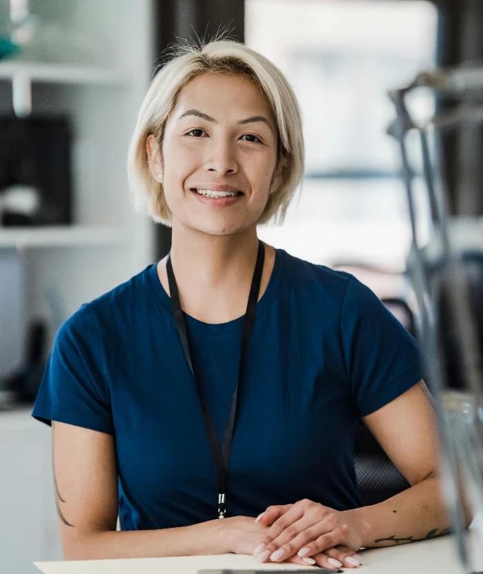 Confident woman smiling while sitting at an office desk, conveying a positive work environment.