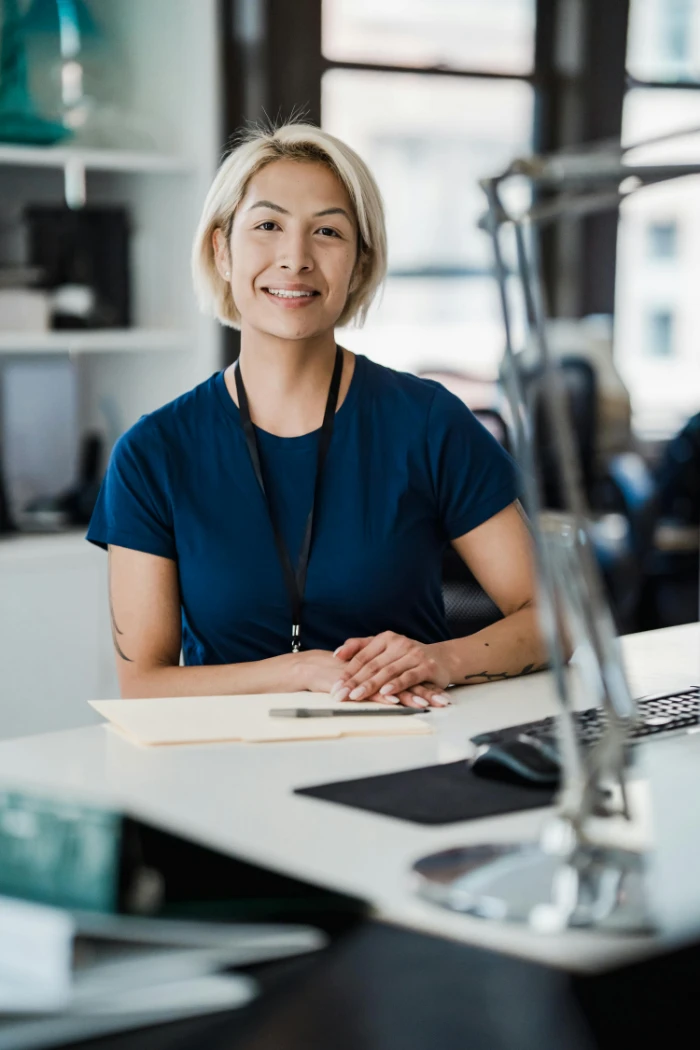 Confident woman smiling while sitting at an office desk, conveying a positive work environment.
