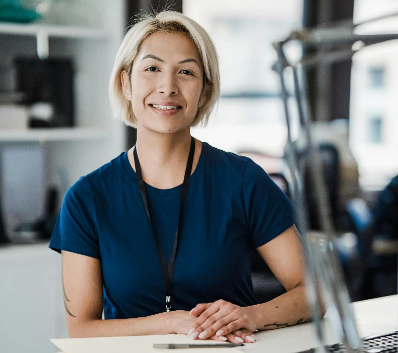 Confident woman smiling while sitting at an office desk, conveying a positive work environment.
