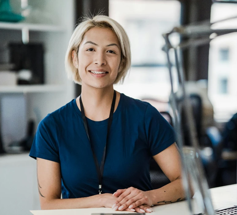 Confident woman smiling while sitting at an office desk, conveying a positive work environment.