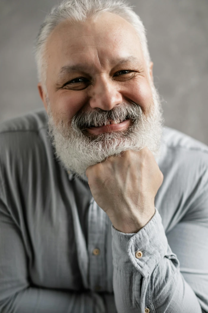 Portrait of a cheerful senior man with a grey beard smiling warmly.