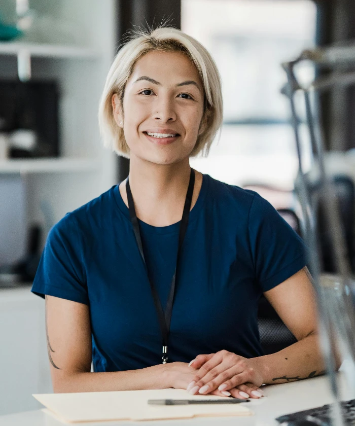 Confident woman smiling while sitting at an office desk, conveying a positive work environment.